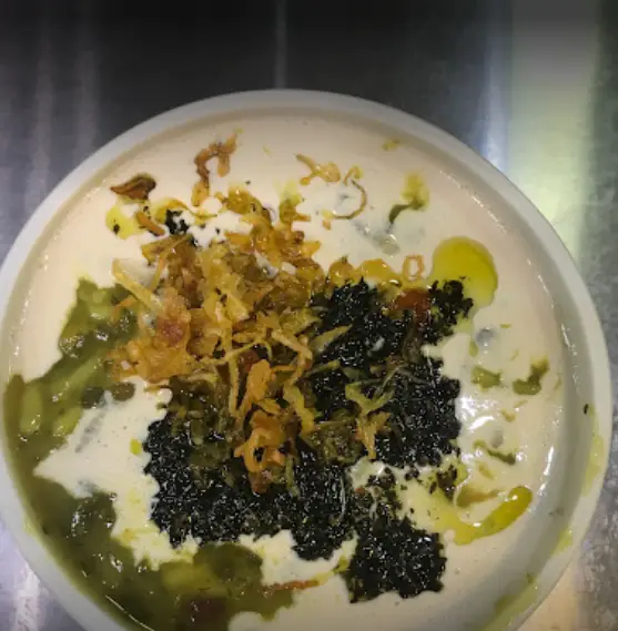 یک کاسه آش سنتی و خوشمزه از آش و حلیم حاج مهدی، با تزئین کشک، نعناع داغ و پیاز داغ طلایی، غذایی گرم و دلپذیر ایرانی.