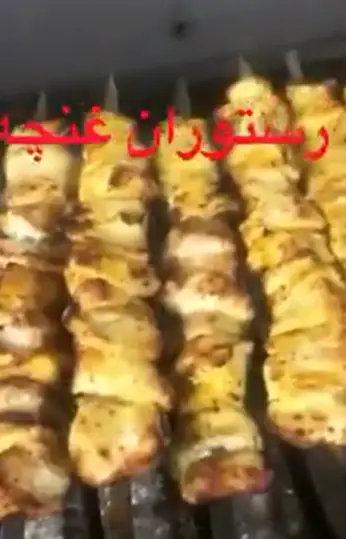 چند سیخ جوجه کباب طلایی و لذیذ در حال پخت بر روی آتش، تصویری جذاب از غذاهای باکیفیت و خوش‌طعم رستوران غنچه.