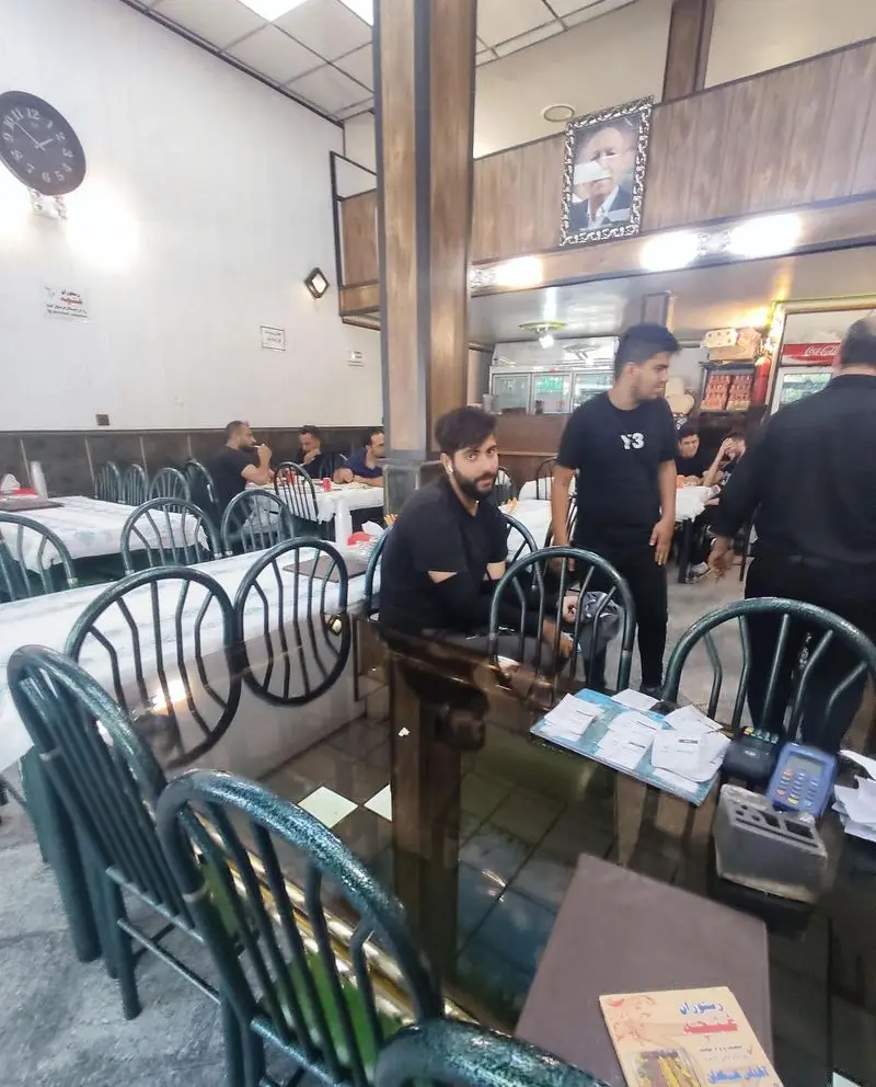 نمایی از فضای داخلی رستوران غنچه با مشتریان و پرسنل فعال، میزهای چیده شده و صندلی‌های سبز تیره در محیطی گرم و دلنشین.