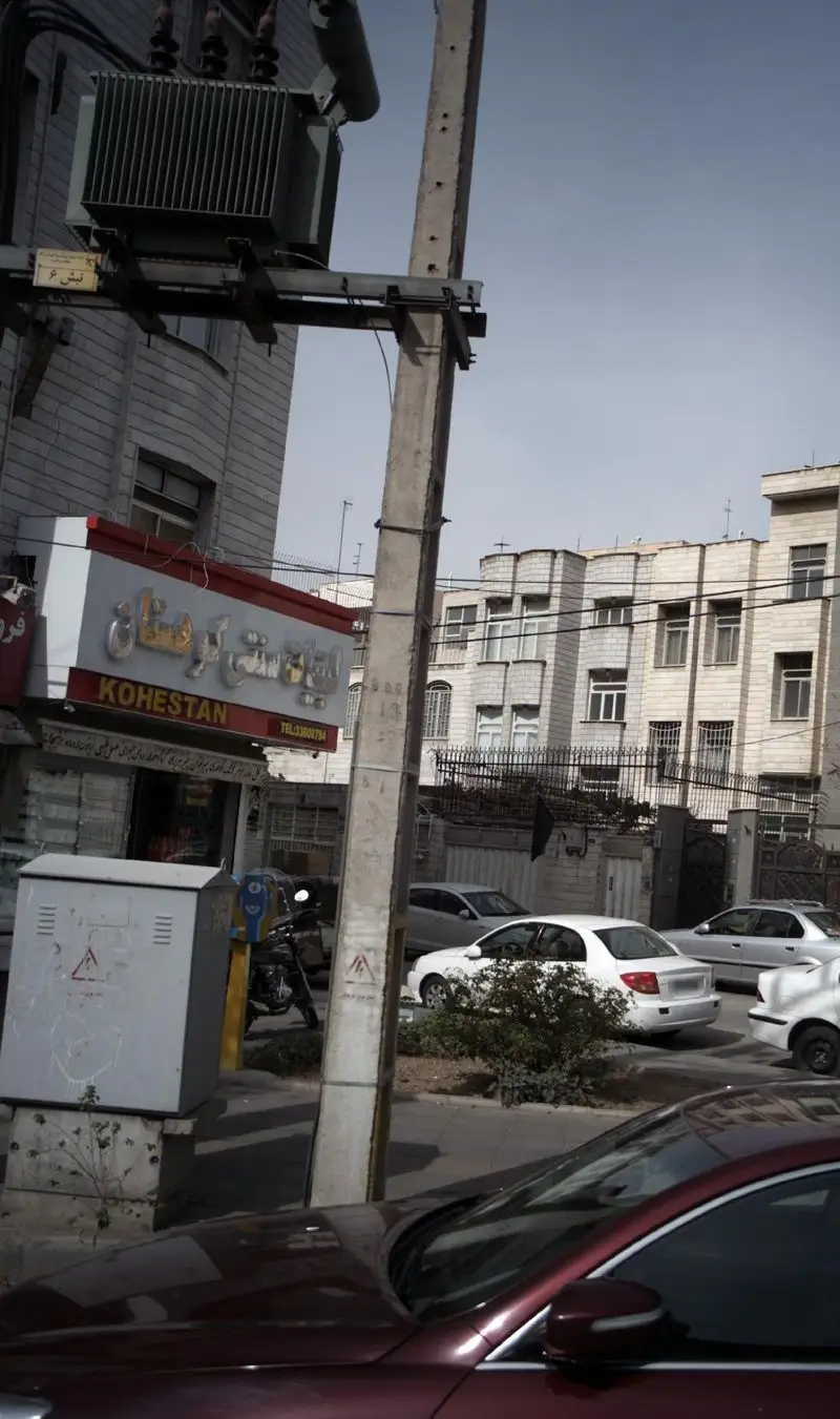 نمای خیابانی از فروشگاه لبنیات سنتی کوهستان، با تابلوی درخشان لبنیات سنتی کوهستان و خودروهای پارک شده در کنار خیابان.