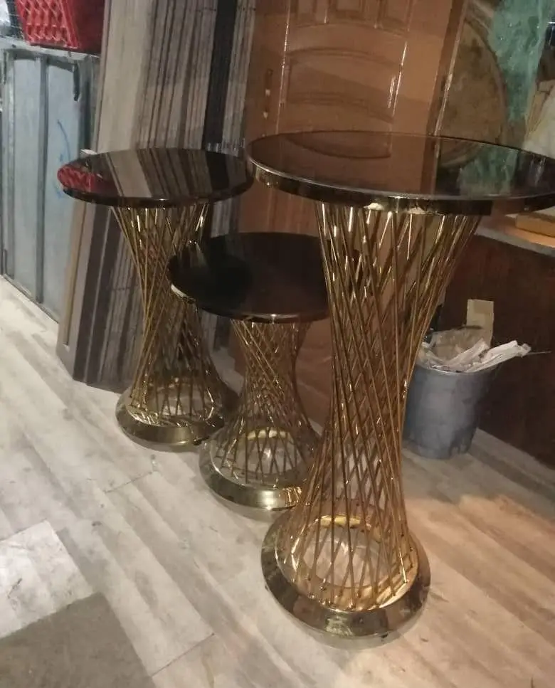 میزهای پذیرایی و تشریفات مدرن طلایی با پایه استوانه ای فلزی و صفحه شیشه ای تیره، آماده اجاره برای انواع مجالس و ایونت ها از تجهیزات کرایه ستاره.