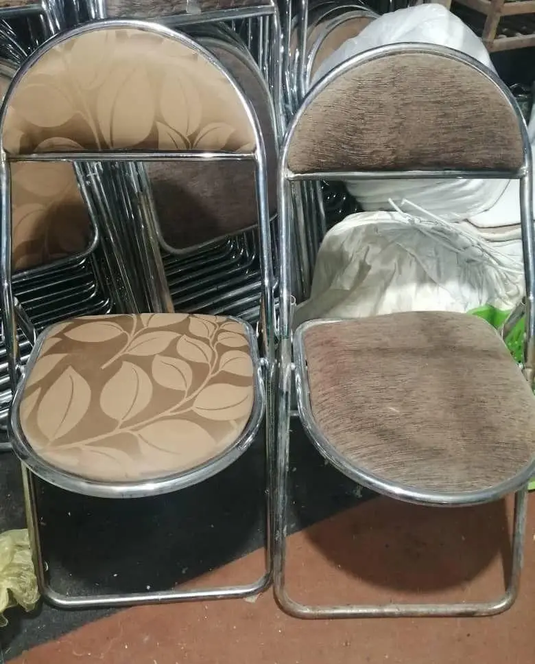 تصویر دو صندلی تاشو شیک با فریم استیل و روکش پارچه‌ای قهوه‌ای، مناسب کرایه در مجموعه تجهیزات و ظروف کرایه ستاره.