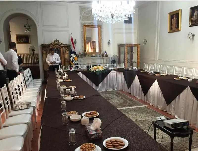 سالن اجتماعات مجلل با میز یو شکل، رومیزی قهوه‌ای، صندلی‌های سفید و پذیرایی، نمونه‌ای از تجهیزات و ظروف کرایه ستاره برای مراسم رسمی.