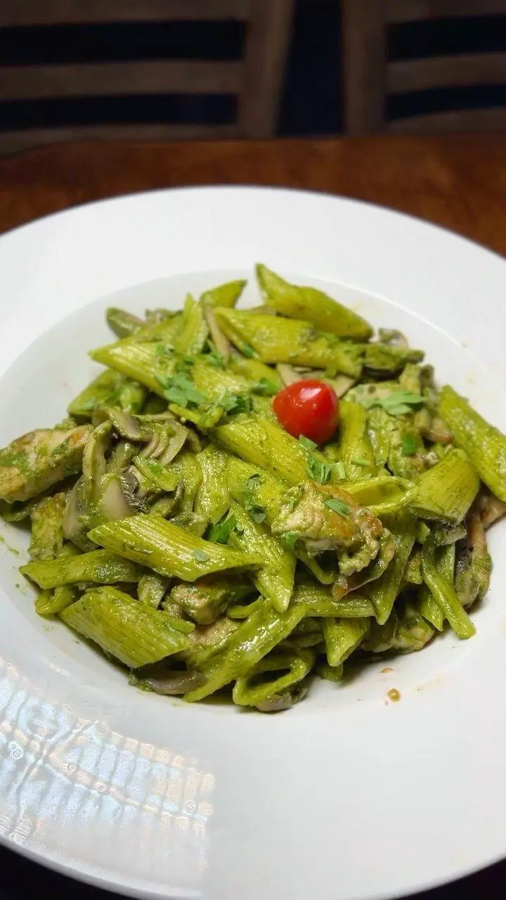 پاستا پنه سبز با سس پستو، تکه‌های مرغ و قارچ، غذایی پرطرفدار از کافه رستوران هریک. ایده‌آل برای دوستداران طعم‌های خاص.