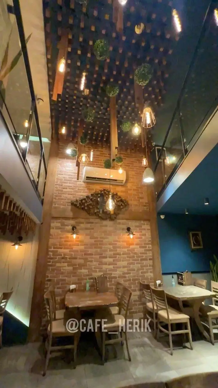 دکوراسیون داخلی کافه رستوران هریک با سقف خلاقانه، آجرنما، نورپردازی گرم، میز و صندلی‌های چوبی و فضای دوطبقه دلنشین.