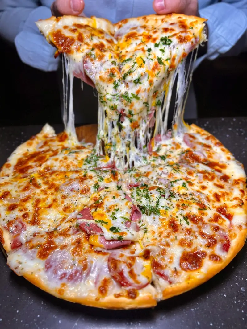 لذت طعم بی‌نظیر پیتزای داغ و پنیر کشدار در کافه رستوران هریک، تجربه‌ای خوشمزه از بهترین غذاهای ایتالیایی.