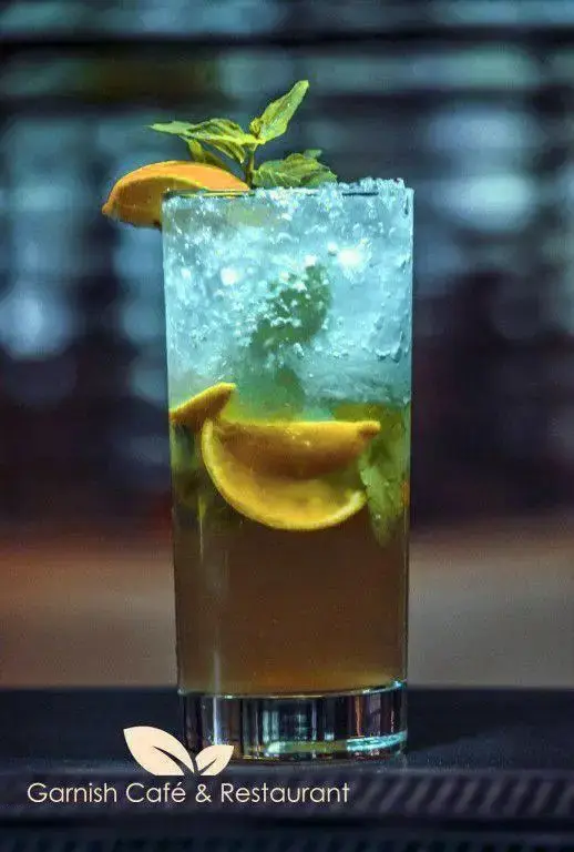 نوشیدنی گوارا و خنک لیموناد یا موهیتو با یخ فراوان، برگ‌های نعناع و اسلایس پرتقال، انتخابی ایده‌آل در کافه رستوران گارنیش.