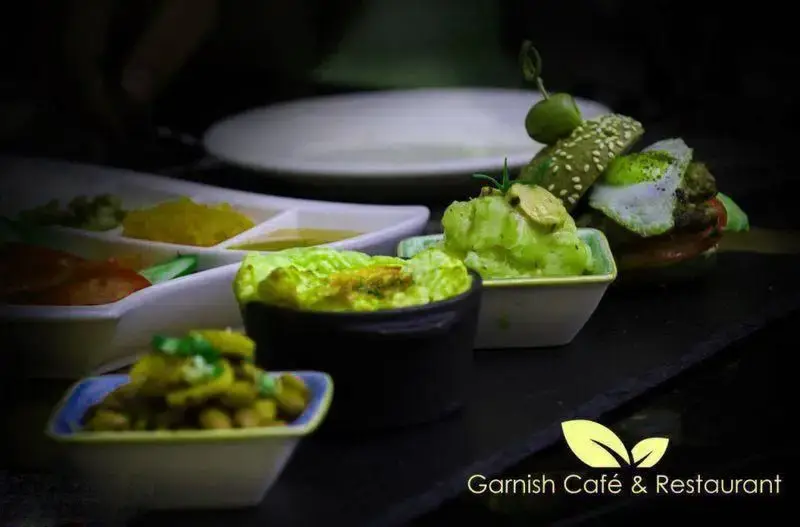 نمایی جذاب از غذاهای متنوع و خوشمزه کافه رستوران گارنیش، شامل پیش‌غذاهای سالم و یک مینی برگر سبز، تجربه ای دلپذیر برای مشتریان.