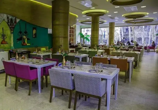 فضای داخلی شیک و مدرن کافه رستوران گارنیش با میز و صندلی‌های رنگارنگ و دکوراسیون چشم‌نواز، آماده پذیرایی از مشتریان است.