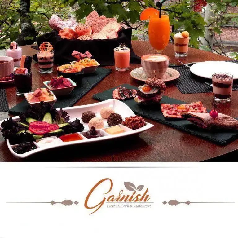 میز پر از صبحانه و برانچ متنوع و لذیذ در کافه رستوران گارنیش، شامل نوشیدنی، شیرینی و خوراکی‌های رنگارنگ با فضایی دلنشین.