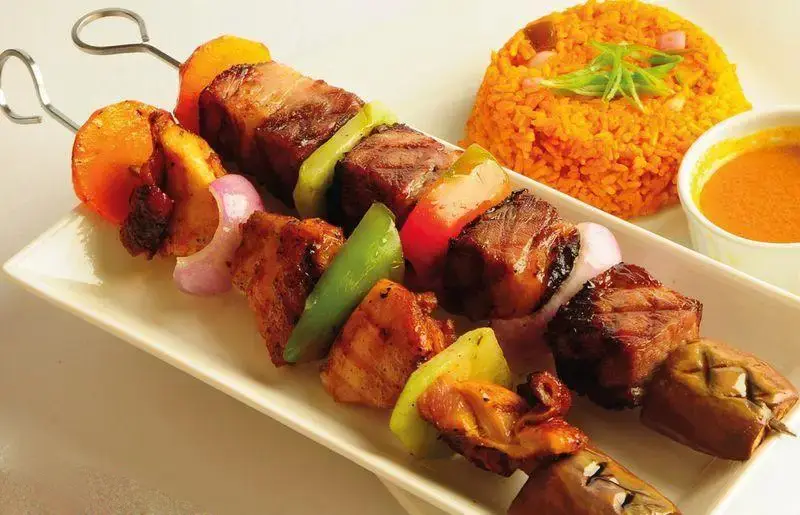 سیخ‌های کباب گوشت و مرغ گریل شده با فلفل دلمه‌ای، پیاز و بادمجان، سرو شده با پلو نارنجی و سس مخصوص کافه رستوران گارنیش.