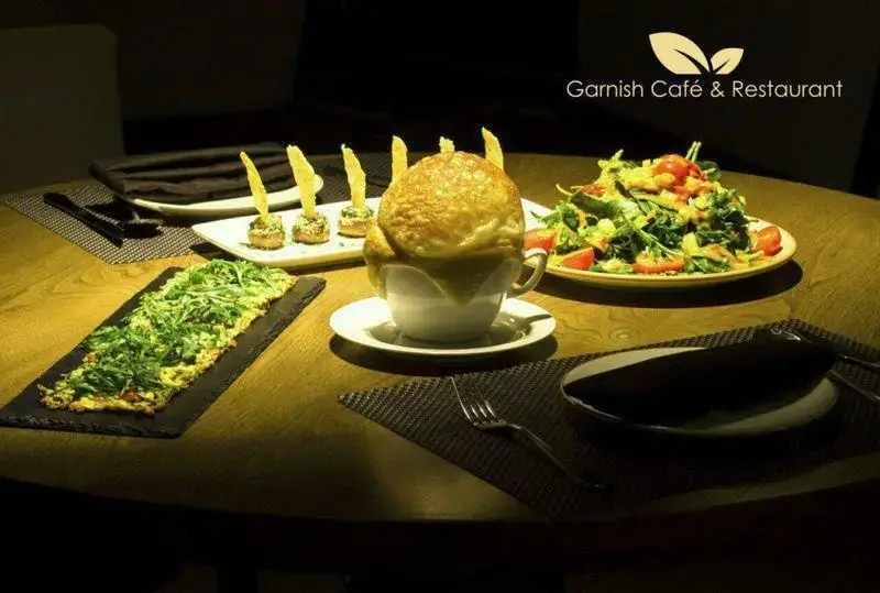 تصویری جذاب از میز غذا در کافه رستوران گارنیش، شامل سوپ پفکی، سالاد تازه با گوجه و انواع پیش غذاهای لذیذ.