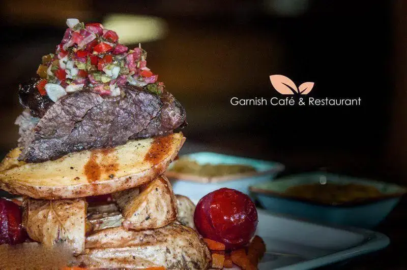 نمایی نزدیک از استیک و سیب‌زمینی تنوری در کافه رستوران گارنیش، مناسب برای تجربه یک غذای لذیذ و دلپذیر.