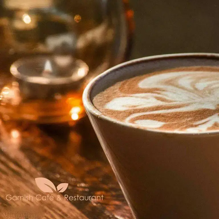 لذت نوشیدن قهوه لاته آرت در فضایی دنج و گرم. فنجان قهوه با طراحی هنری زیبا، نمادی از کیفیت و آرامش در کافه رستوران گارنیش.