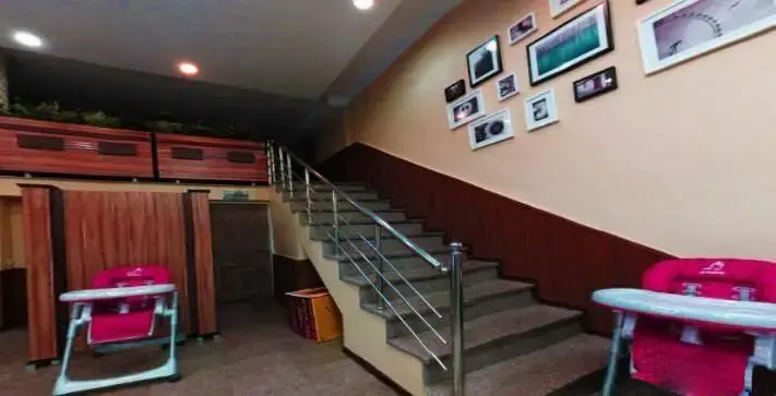 نمایی از دکوراسیون داخلی رستوران مسعود با راه پله شیک، گالری عکس دیواری و صندلی‌های مخصوص کودک جهت رفاه خانواده‌ها.