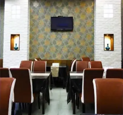 فضای داخلی جذاب و شیک رستوران مسعود با میز و صندلی‌های راحت چرمی، دیوارپوش طرح‌دار، تلویزیون و دکوراسیون مدرن برای راحتی مشتریان.