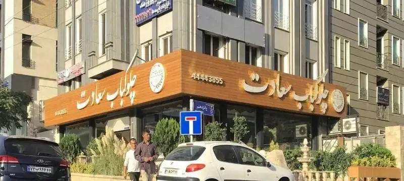 نمای بیرونی رستوران چلوکباب سعادت با تابلوی چوبی و طلایی، نمایش دهنده نام و شماره تماس 44443855 برای بهترین غذای ایرانی.