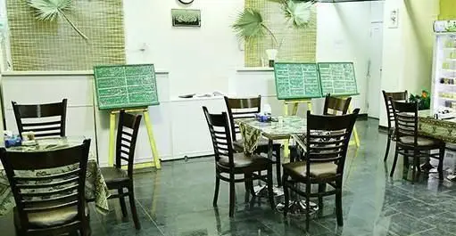 فضای داخلی دلنشین رستوران و کافه زندگی بهشتی با میز و صندلی‌های چوبی، منوهای روی استند و محیطی آرام برای تجربه غذایی عالی.