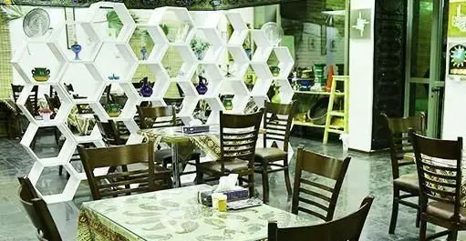 فضای داخلی زیبای زندگی بهشتی با پارتیشن‌های مدرن شش‌ضلعی سفید، گلدان‌های سرامیکی رنگارنگ، میز و صندلی‌های چوبی و فضایی آرام‌بخش.