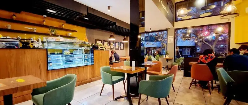 فضای داخلی کافه ویونا با دکوراسیون مدرن، پیشخوان جذاب کیک و شیرینی، میز و صندلی‌های راحت و مشتریان در حال لذت بردن از محیط