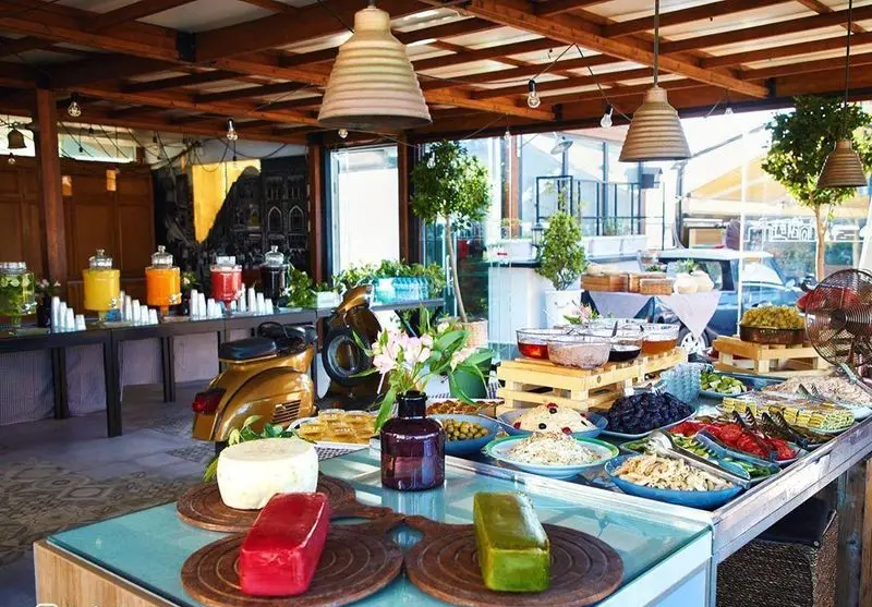 بوفه صبحانه و برانچ جذاب کافه شمرون شامل خوراکی‌های لذیذ، میوه‌های تازه، نوشیدنی‌های رنگارنگ در فضایی مدرن و روشن.