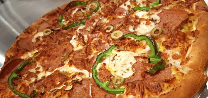 پیتزای تازه و خوشمزه پیتزا سرخاب سیب با برش‌های کالباس، سوسیس، فلفل دلمه سبز و زیتون. پنیر طلایی و نان برشته آماده سرو.