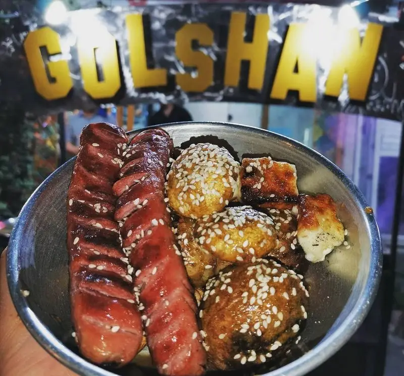 تصویری از سوسیس کبابی و کوفته‌های کنجدی در ظرف فلزی. غذای داغ و لذیذ جگرسرای گلشن. بهترین طعم غذای خیابانی در گلشن.