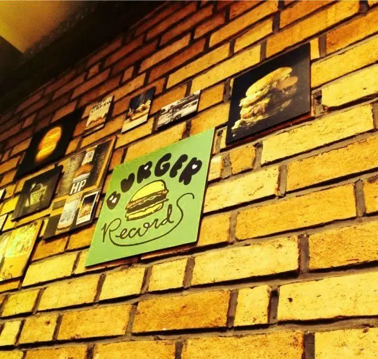 دکوراسیون داخلی منحصربه‌فرد رستوران بلک برگر با دیوار آجری، تابلوهای هنری و عکس‌های اشتهاآور برگر، ایجاد فضایی گرم.