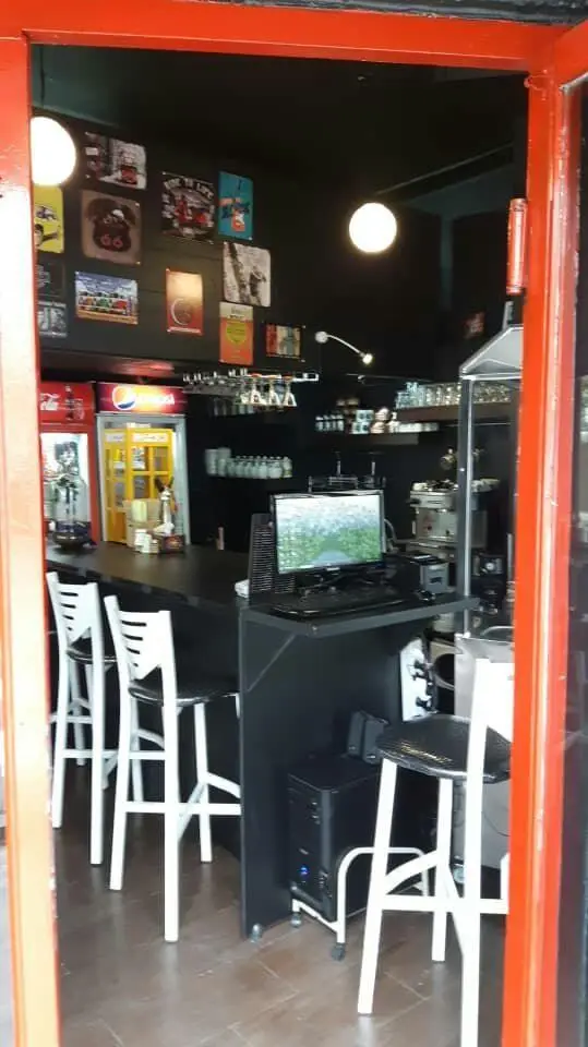 کافه برگر ن: نمای داخلی جذاب با پیشخوان بار، صندلی‌های راحت، کامپیوتر، یخچال‌های نوشیدنی و تزئینات دیواری منحصربفرد.