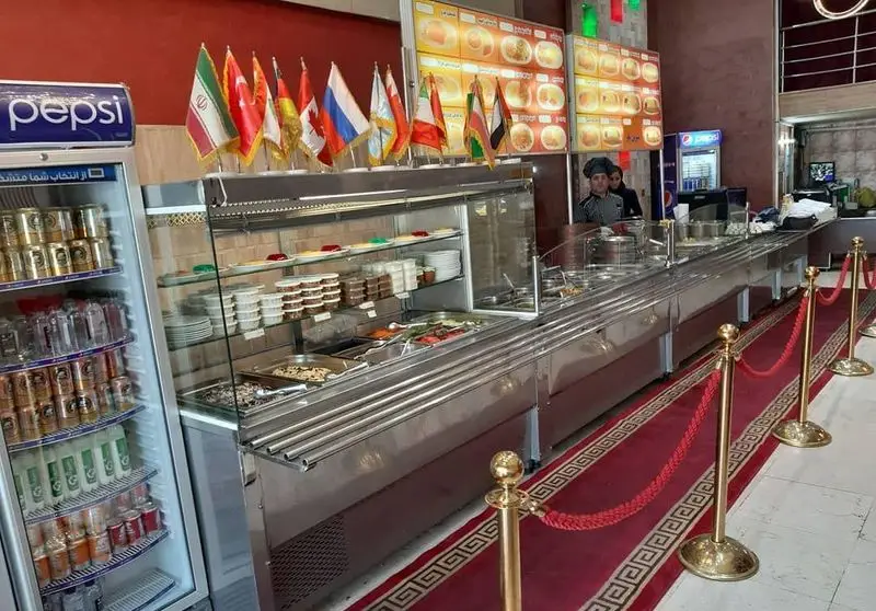 رستوران شماعیان: سلف سرویس متنوع غذاهای ایرانی و بین‌المللی با منوی کامل، نوشیدنی‌های خنک، پرچم‌های ملل و دکوراسیون مجلل.