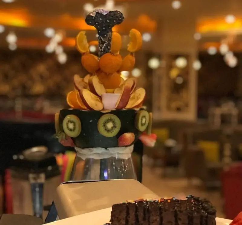 تصویری جذاب از قلیان میوه تازه و کیک شکلاتی لذیذ کافه دایموند. تجربه طعمی متفاوت در فضایی دلنشین و شیک.