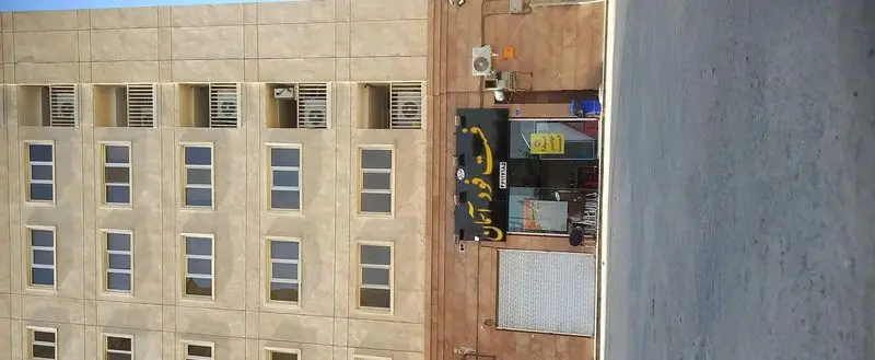 تصویر ساختمان فست فود آسمان با تابلوی مشکی و حروف زرد، نمایشگر نمای شهری مغازه غذا و خدمات بیرون بر مشتریان.