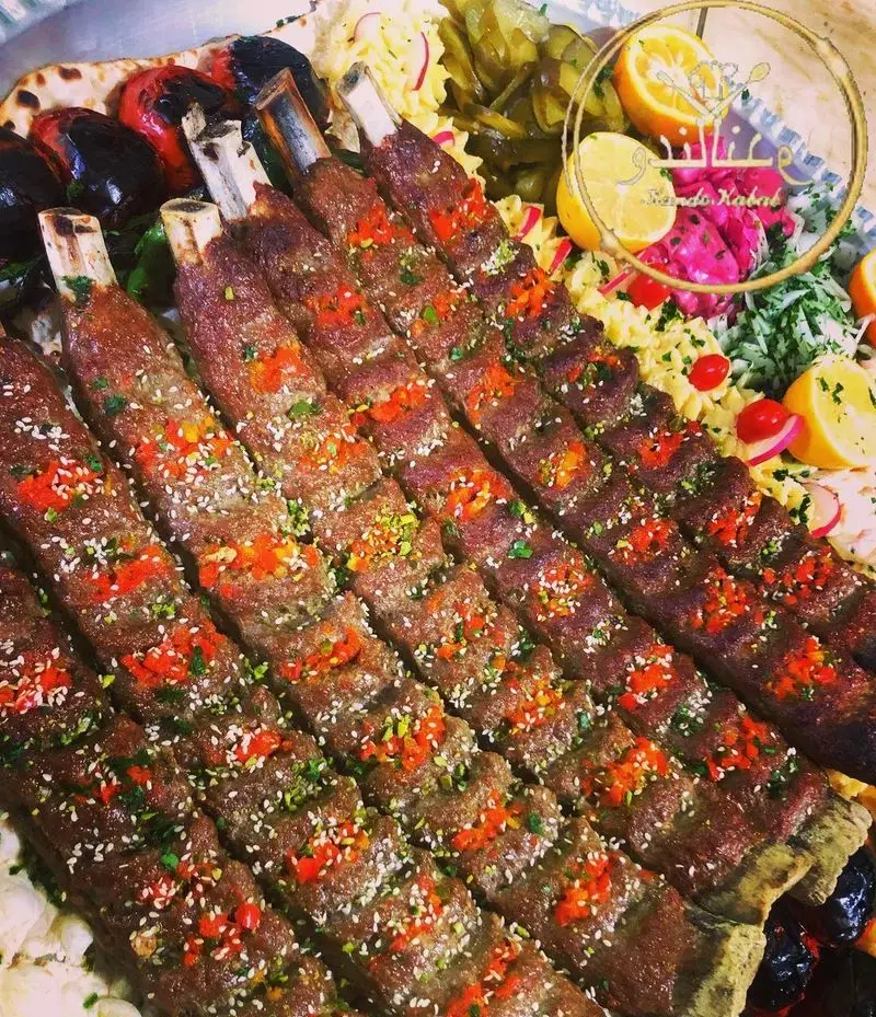 سینی کباب کوبیده کندو کباب بر استخوان با دورچین رنگارنگ لیمو، گوجه، بادمجان و ترشیجات؛ غذای سنتی ایرانی.