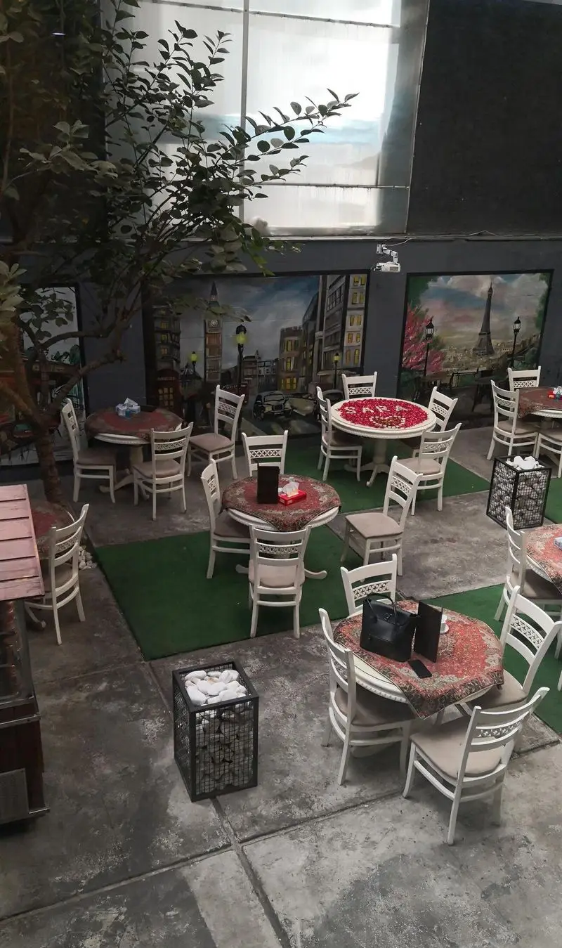 کندو کباب: محیط دلنشین رستوران با دکوراسیون شیک. میزهای گرد سفید، صندلی‌های راحت و نقاشی‌های زیبای شهرهای اروپایی دیوارهای فضا را دلنشین کرده‌اند.