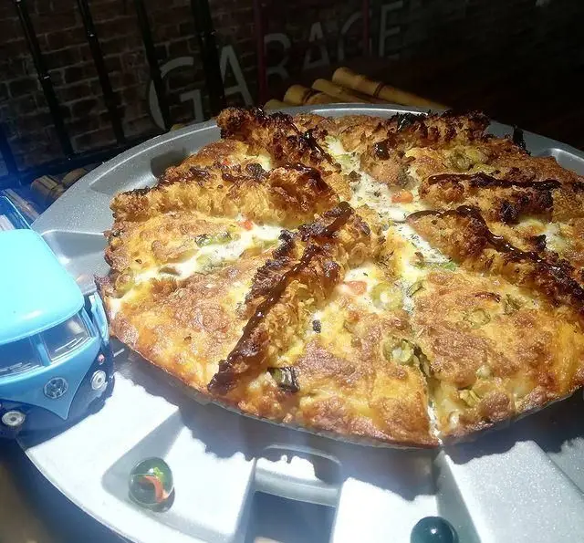 پیتزای بزرگ و پخته فست فود گاراژ با تاپینگ‌های متنوع و سس مخصوص، سرو شده در سینی منحصر به فرد با تم گاراژی. تجربه‌ای متفاوت از طعم واقعی.