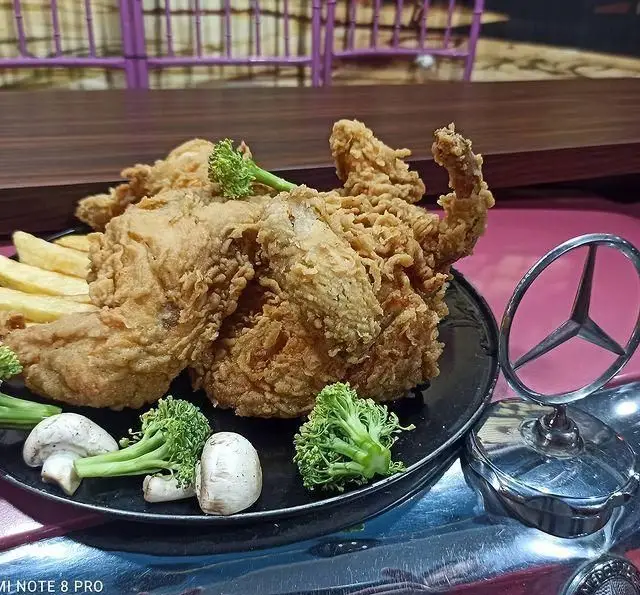 مرغ سوخاری کامل و طلایی فست فود گاراژ به همراه سیب زمینی، قارچ و بروکلی. غذایی دلپذیر در محیطی با طراحی منحصر به فرد خودرویی.