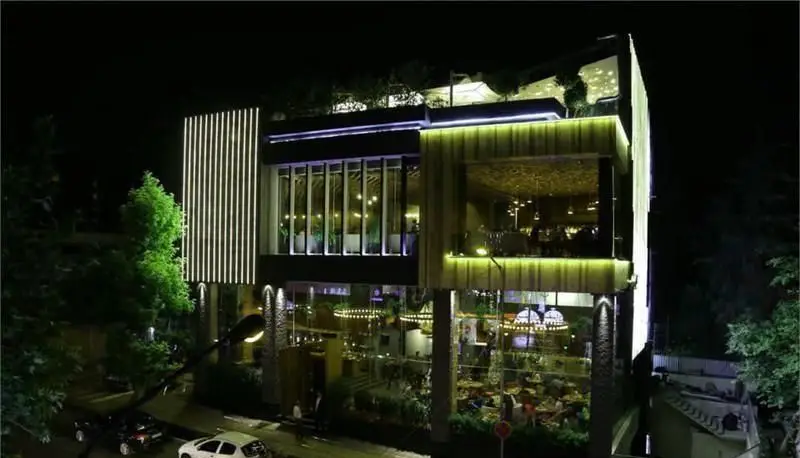 نمای بیرونی کافه رستوران کاپیتان لانژ در شب با نورپردازی خاص و معماری مدرن، مکانی جذاب برای تجربه لحظات دلپذیر و خاص.