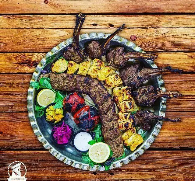 تصویر سینی کباب ترکیبی بزرگ با شیشلیک، کوبیده و جوجه کباب، همراه گوجه کبابی، لیمو و مخلفات، غذای ویژه کاپیتان لانژ.