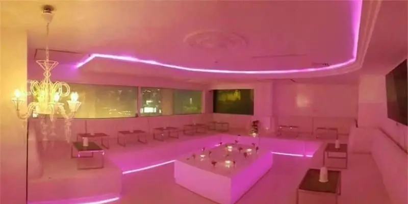 فضای داخلی مدرن و شیک کافی شاپ کاپیتان لانژ با نورپردازی نئون صورتی و مبلمان سفید، محیطی دلنشین برای مشتریان.