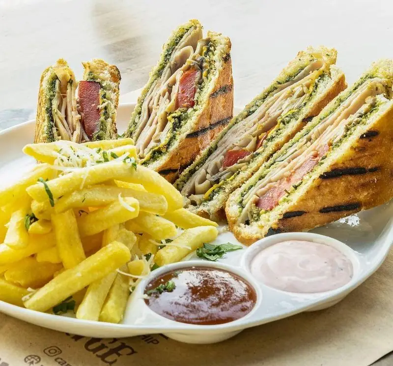 کلاب ساندویچ‌های گریل شده با نان تست، ژامبون مرغ، پستو و گوجه‌فرنگی، سرو شده با سیب‌زمینی سرخ‌کرده و سس‌های متنوع در کاپیتان لانژ.