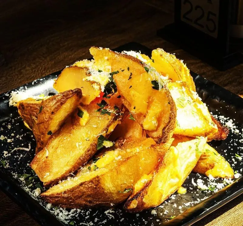 سیب‌زمینی وج ترد و لذیذ غرق در پنیر چدار و پارمزان، با کمی سبزی معطر، گزینه‌ای دلچسب از منوی خاص کافه کاپیتان لانژ برای شما.