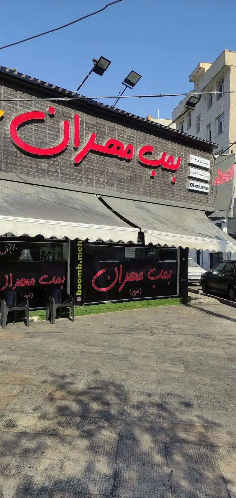 نمای بیرونی جذاب فست فود و رستوران بمب مهران با تابلوهای درخشان قرمز، مکانی عالی برای تجربه طعم لذیذ انواع برگر و غذاهای فست فود.