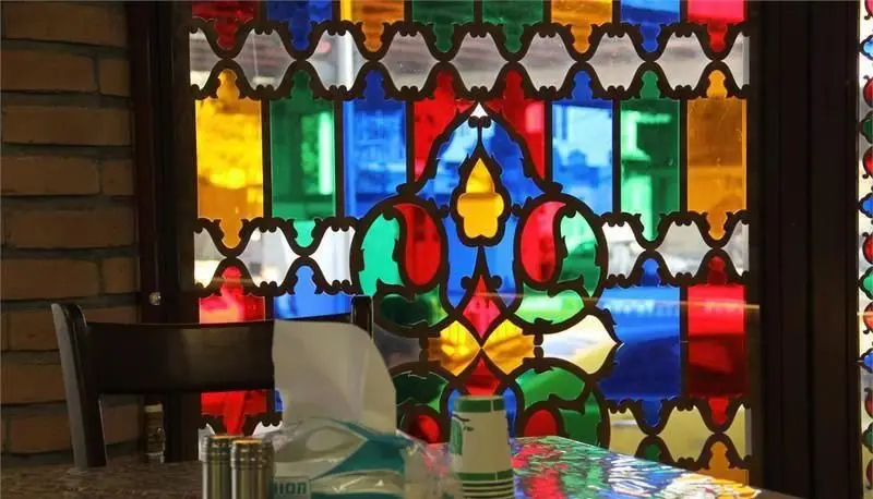 دکوراسیون زیبای رستوران ایرانی ساینا با پنجره ارسی رنگارنگ و طرح‌های سنتی، فضایی دلنشین و اصیل برای مشتریان فراهم کرده است.