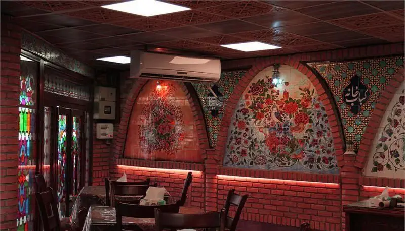 دکوراسیون داخلی چشم‌نواز رستوران ایرانی ساینا با دیوارهای آجری، طاق‌های کاشی‌کاری شده گل و مرغ و پنجره‌های شیشه‌رنگی سنتی.