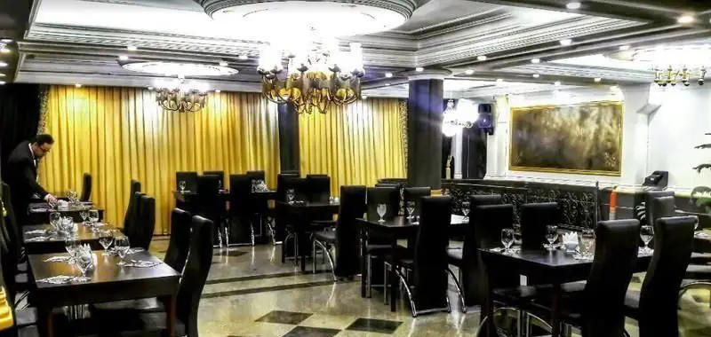 فضای داخلی شیک و مجلل رستوران ایرانی نامی سرو، با میز و صندلی‌های چیده شده و دکوراسیون طلایی، آماده پذیرایی از میهمانان.