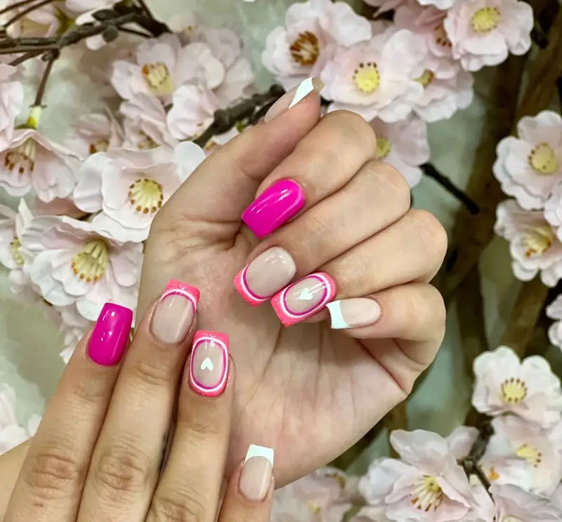 طراحی ناخن ژلیش صورتی پررنگ و فرنچ اکلیلی با طرح قلب و فلش در سالن تخصصی ناخن زهرا نریمان. بهترین انتخاب برای کاشت ناخن شیک و جذاب.