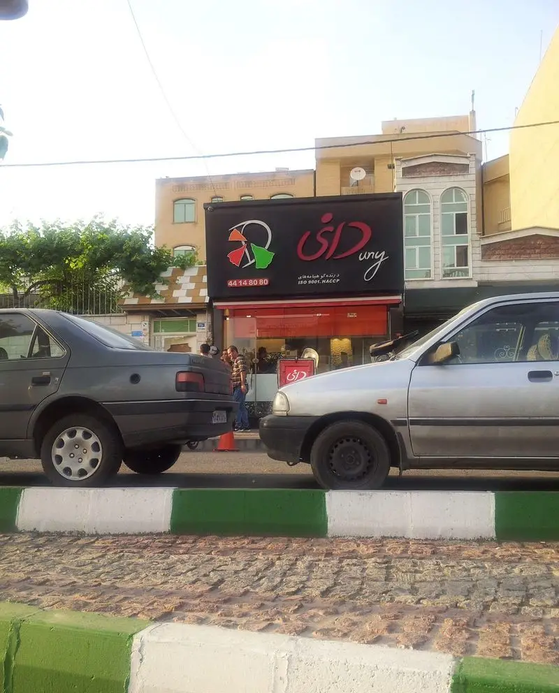 تصویر تابلوی بزرگ و جذاب پیتزا دانی با لوگو و شماره ۴۴۱۴۸۰۸۰، نشان‌دهنده استانداردهای ISO و HACCP در محیط شهری و خودروها.