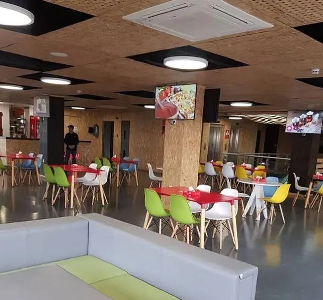 تصویری از محیط داخلی مدرن فست فود پرپروک با طراحی شیک، میز و صندلی های رنگی متنوع، فضایی دلنشین برای صرف غذا.