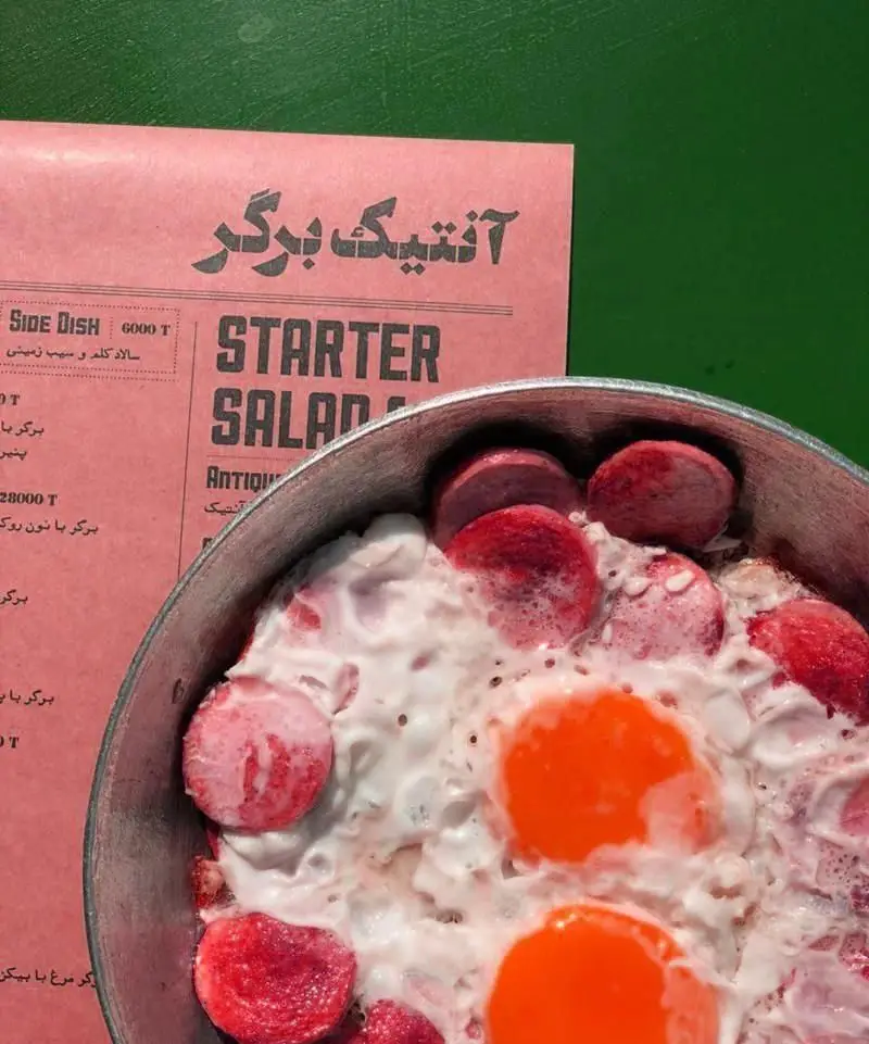 منوی صورتی کسب و کار آنتیک برگر با عنوان "STARTER SALAD" و غذای گرم سوسیس و تخم مرغ نیمرو در ماهیتابه. فست فود.