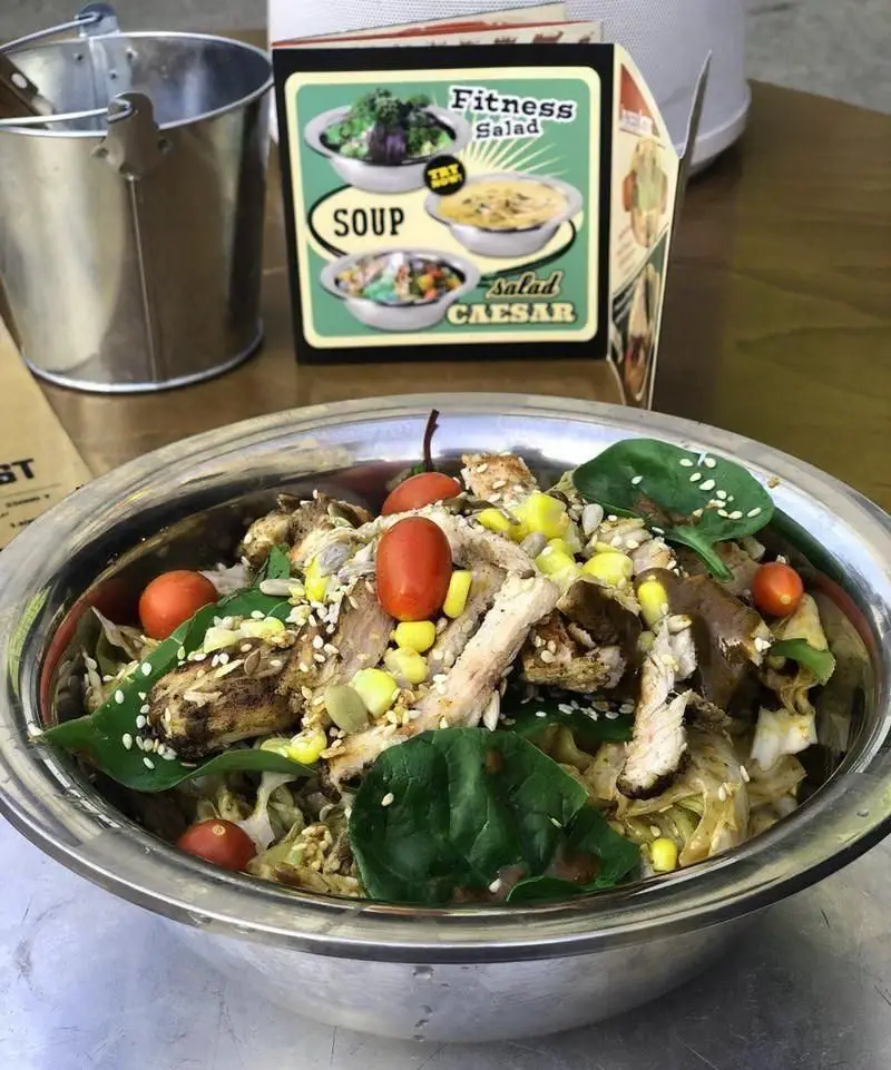 سالاد فیتنس خوشمزه با مرغ گریل شده، گوجه گیلاسی، ذرت، اسفناج و دانه های مغذی در رستوران برگر آنتیک برگر.